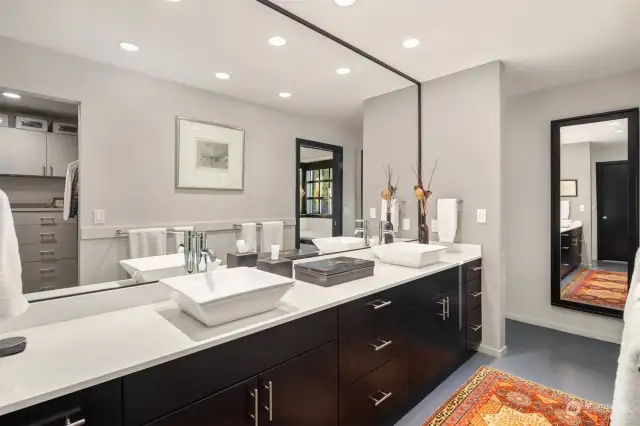 Double sinks in this sophisticated primary bathroom. Walk in closet can be seen in the mirror.