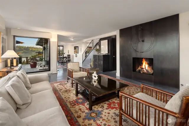 Living room focused on the chic fireplace, surrounded by picture windows.