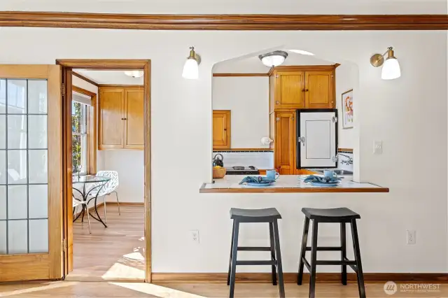 The sun-drenched eat-in kitchen seamlessly connects to the living room’s eating bar, creating a bright and inviting space for cooking, dining, and gathering.