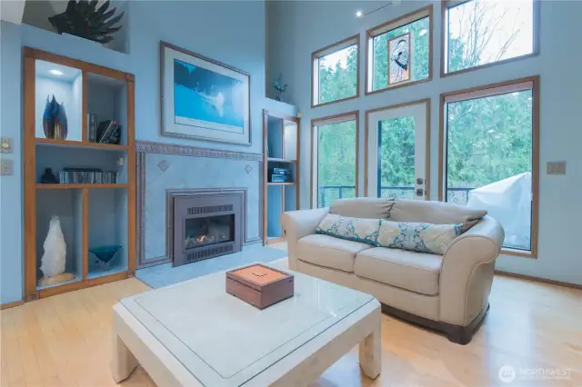 Large living room with cozy gas fireplace with maple hardwood floors.