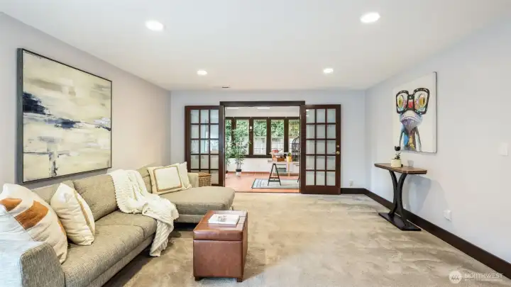 Expansive lower-level living space highlighted by elegant French doors, offering seamless flow into the bright sunroom.