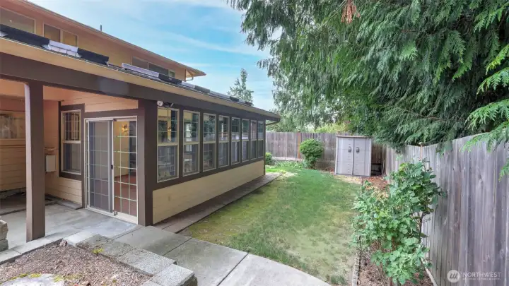 Step out from the sunroom into this charming side yard, perfect for gardening or creating a quiet retreat beneath the trees.