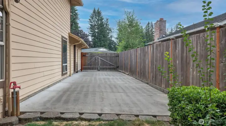 Extended paved side yard with double gate access, perfect for extra parking, storage, or recreational use.