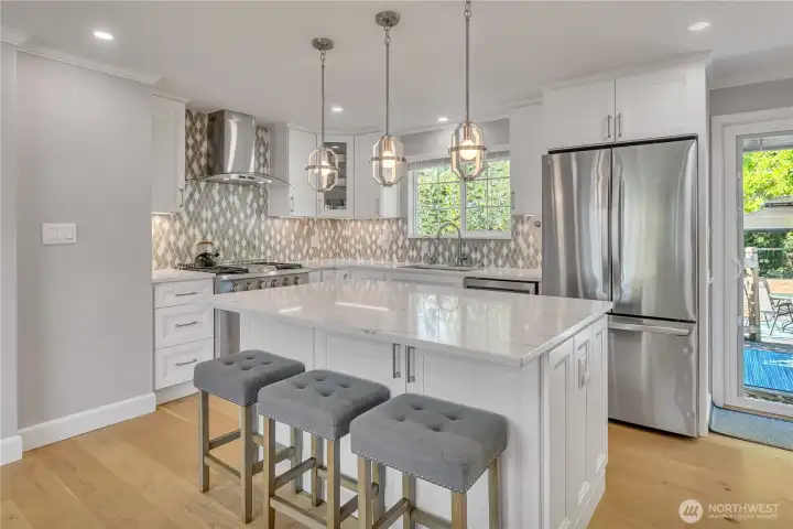 Stylish kitchen with quartz island, custom tile backsplash, and modern pendant lighting.