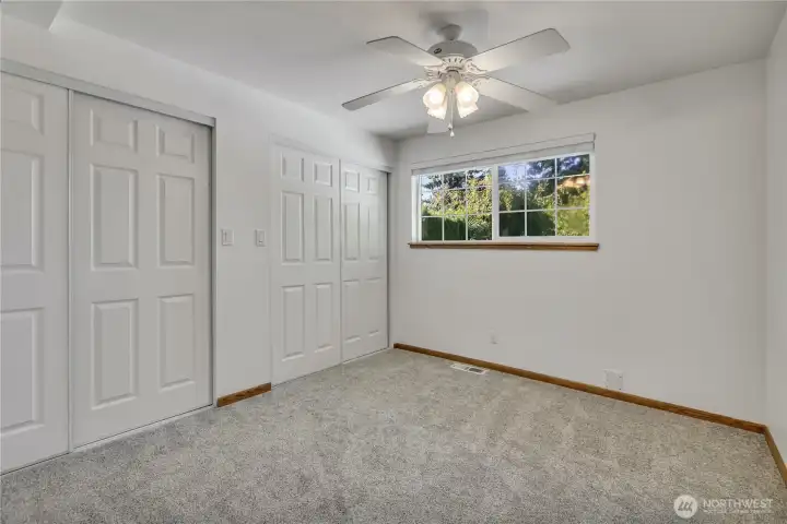 Spacious bedroom with new carpet, dual closets, and views of the backyard.