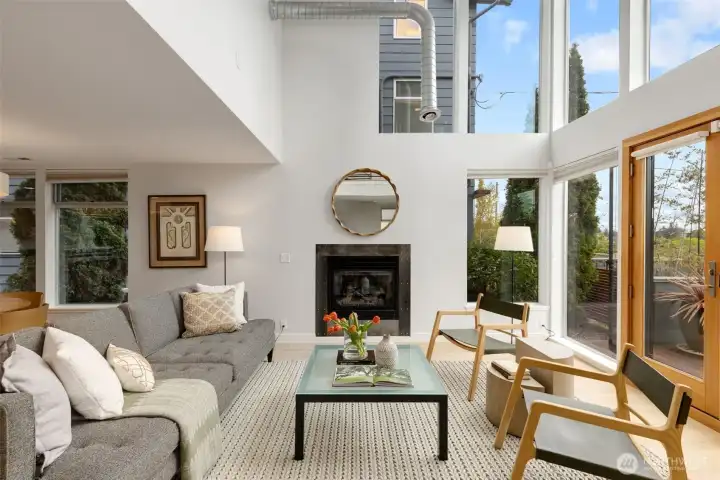Living room with gas fireplace basks in eastern light streaming from floor to ceiling windows