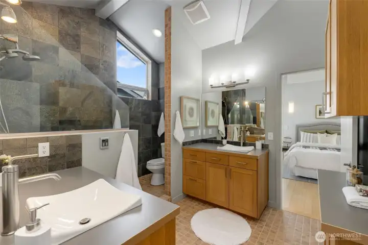 Modern, third floor bathroom featuring dual sinks, a tiled shower and abundent storage