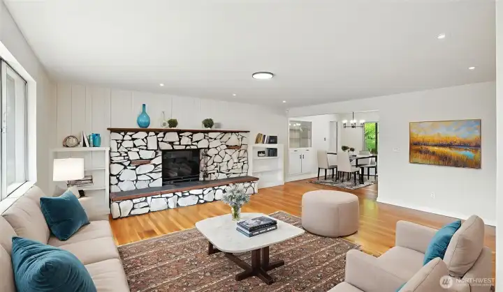 Large, sunlit living room, with solid hardwood floors and wood-burning fireplace. Virtually staged.