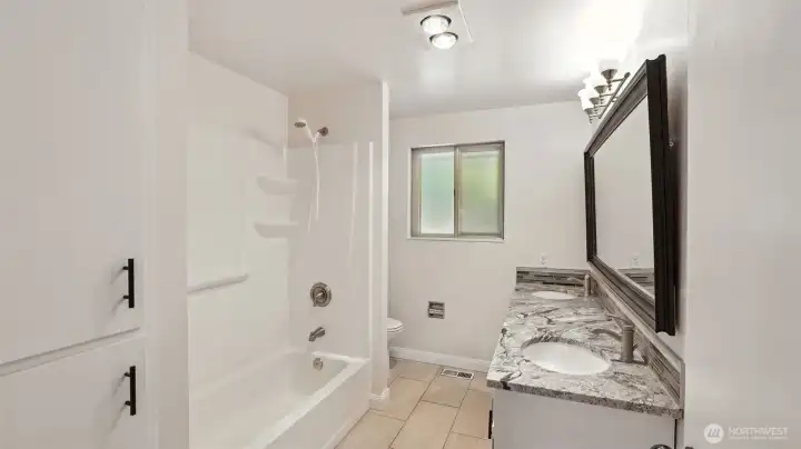 Main Hall Full Bath, with newer ceramic tile flooring, double sink vanity, light fixture and countertop.