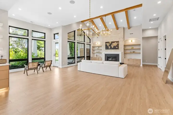 Open-concept great room with exposed beams, custom built-ins, gas fireplace, and abundant natural light.