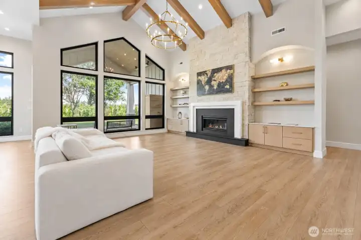 ight-filled great room showcasing architectural beams, floor-to-ceiling stonework, and seamless indoor-outdoor living.