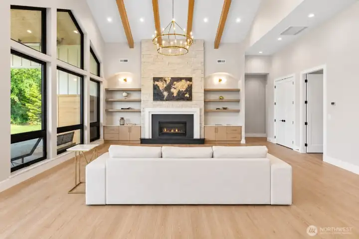 Vaulted living space with custom built-ins, gas fireplace, and expansive windows framing the backyard retreat.