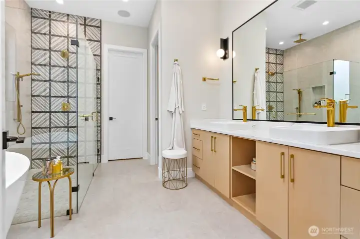 Designer primary ensuite featuring custom tile accents, dual vanities, a spacious walk-in shower, and a relaxing soaking tub designed for everyday luxury.