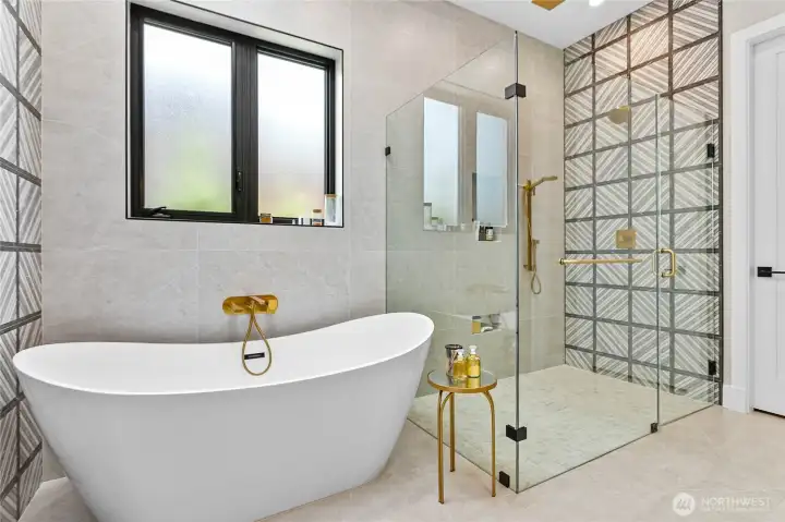 Luxury primary ensuite showcasing a freestanding soaking tub, expansive glass-enclosed shower, dual-sink vanity, and elegant designer finishes.