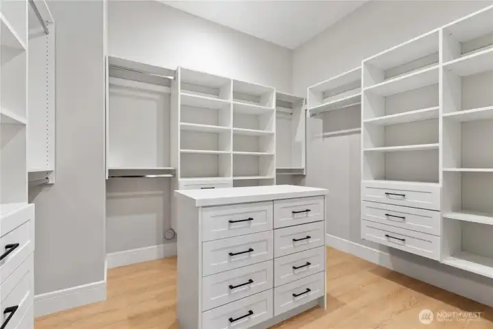 Spacious custom walk-in closet with built-in cabinetry, abundant shelving, drawer storage, and a center island for effortless organization.