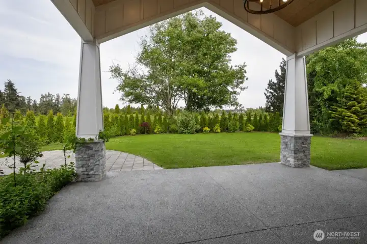 Spacious covered patio with stone accents, vaulted ceilings, and peaceful views of the surrounding landscape