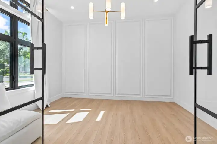 Dedicated home office or flex space located just off the main entry, featuring abundant natural light, custom wall detailing, and the perfect setup for remote work, a study, creative studio, or optional guest room.
