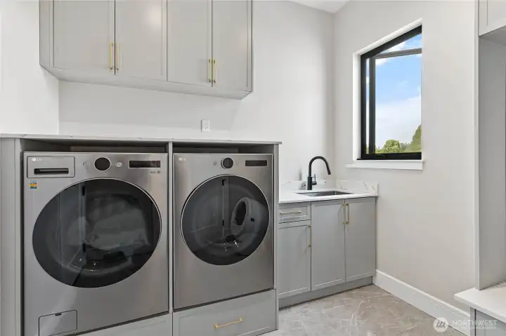 Laundry Room    Conveniently located between the garage and kitchen, this thoughtfully designed laundry room serves as a functional everyday hub. Featuring built-in cabinetry, utility sink, ample storage, and workspace for folding and organization, the space provides a seamless transition from the garage while keeping household tasks efficient and out of sight.