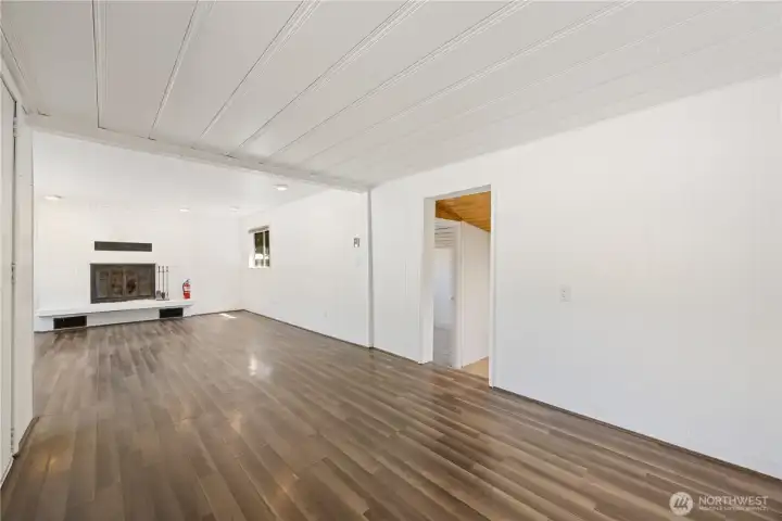 The house opens into a large living room area that spans the full width of the house.  The wood fireplace is on the east end of the room.