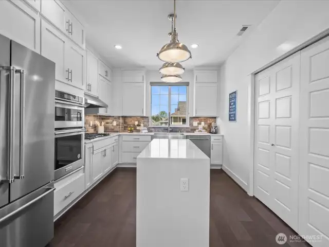 Gorgeous with floor-to-ceiling cabinetry, quartz waterfall island, upgraded appliances, gas cooktop double oven, large pantry, and sunset view!