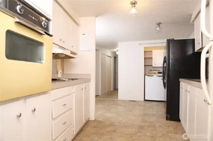 The kitchen offers a clear view into the laundry area, maintaining a functional and connected layout.