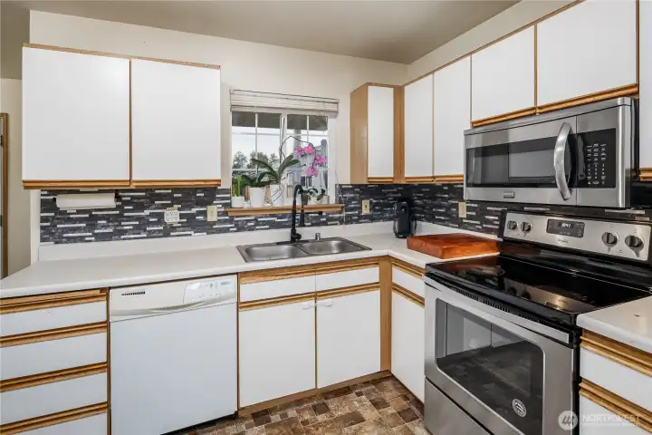 The kitchen has a beautiful backsplash, lots of cabinetry & working space...even the fridge stays,