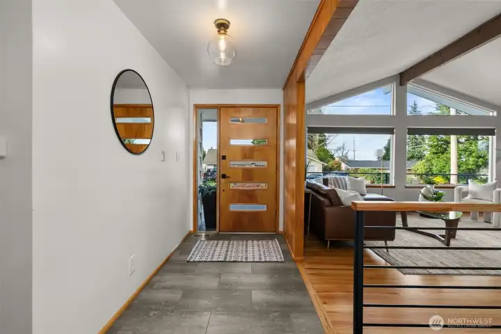 A look back toward the entry shows a perfect example of the balance of modern upscale finishes & convenience (new stair rail, durable lux vinyl plank floor in entry, and stylish new door & lighting) against the backdrop of original character.