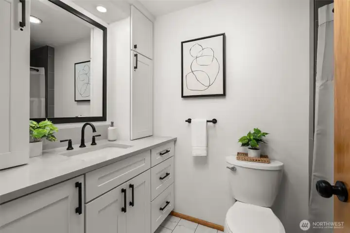 The hall bath is filled with fresh luxe updates - new vanity & storage, tiled floor, stylish tiled tub surround, new fixtures & hardware.