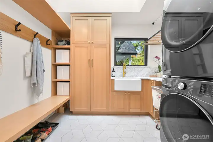 Convenience meets thoughtful design in the main floor laundry room, a true multitasking marvel. This space isn’t just functional—it’s elevated, featuring built-ins that provide a seamless flow and drop zone for life’s everyday necessities. Countertops offer plenty of room for folding and organizing, while heated tile floors add a touch of indulgent warmth to your daily routine. It’s a detail that ensures even household chores feel like a luxury.