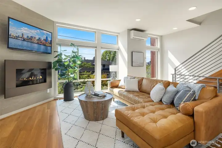 Expansive windows frame the neighborhood and fill the living space with light, anchored by a sleek gas fireplace.