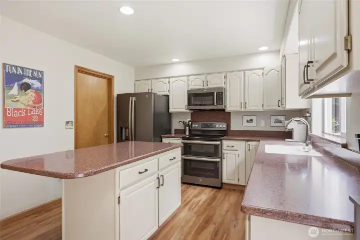 Large kitchen with island, solid surface countertops and stainless-steel appliances.