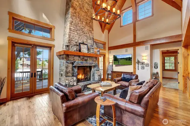Living room with rugged stone fireplace, vaulted ceilings and beams.