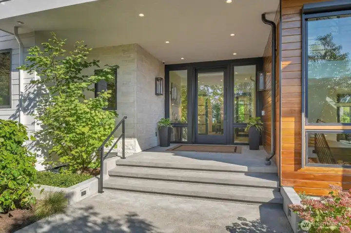 Outdoor accent lighting and interesting textures frame the entry to this residence
