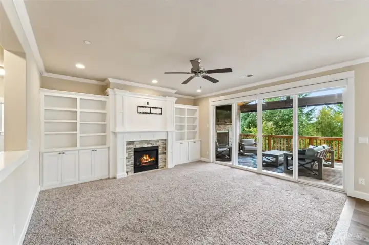Living room with freshly painted built-ins, remote control shades, and large sliding glass doors leading our to the patio