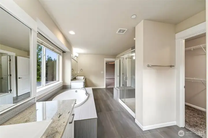Primary bath with dual vanities, fully tiled shower, large soaking tub