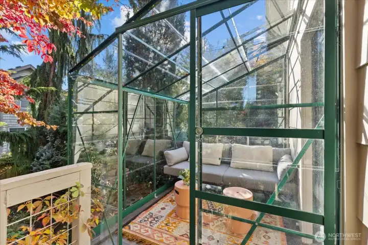 The glass-enclosed sunroom extends living space year-round — perfect for morning coffee, reading, or entertaining.