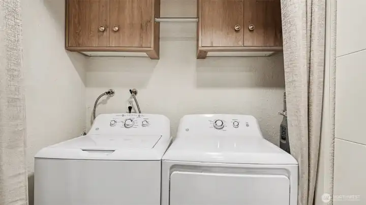 Washer and dryer with storage cabinets and hanging space.