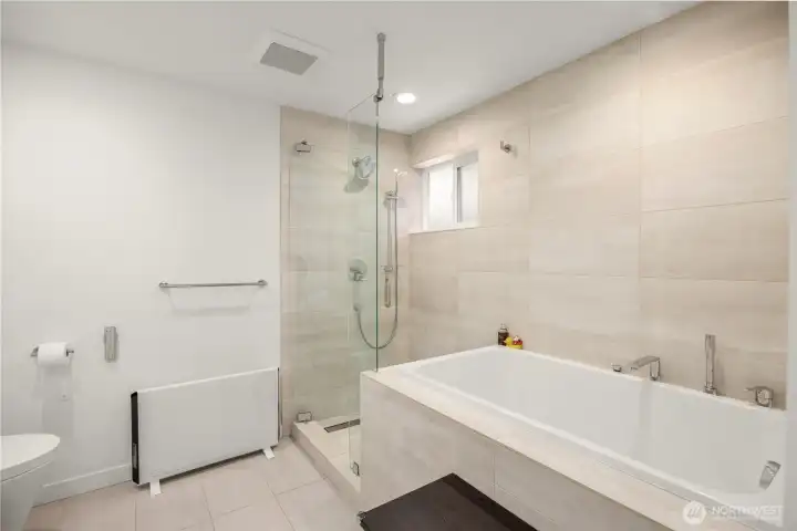 En suite bathroom featuring a Duravit soaking tub, separate tiled shower stall, a sleek TOTO wall-hung toilet (partial view), and radiant heated floors.