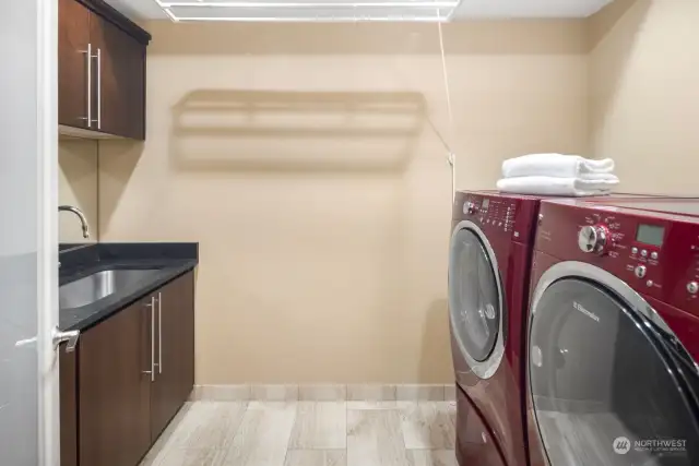 A full-sized laundry room on the second level, complete with cherry-red LG side by side washer and dryer on storage pedestal drawers, makes chores a delight.