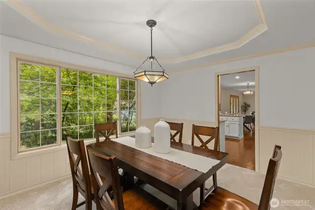 Formal dining room with wainscoting and tray ceiling.