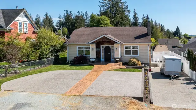 Paved parking in both the driveway and in front of the house with stamped concrete pathway.