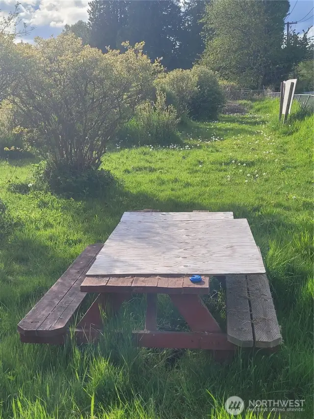 Picnic table up by front gate next to stand shed, painted to match.  Plywood on it temporarily until a repair is made.
