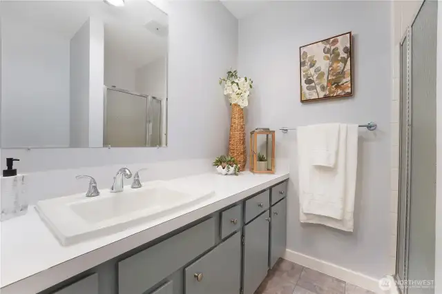Close up of the Primary bathroom with walk in shower.  Vinyl tile flooring and new hardware on the vanity