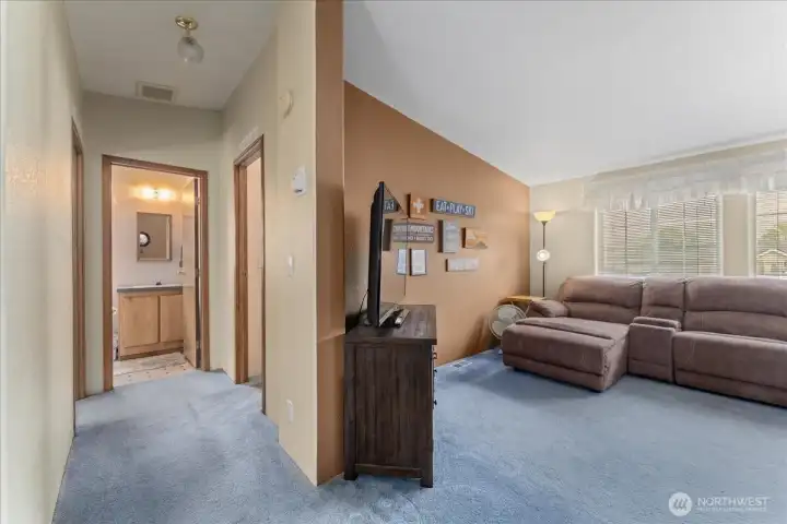 View from the living room down the hallway toward the entrances to the second and third bedrooms and shared bathroom