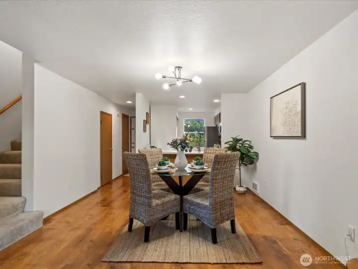 Dining space has updated lighting, with stairs leading to the second floor and utility/storage closet to the left