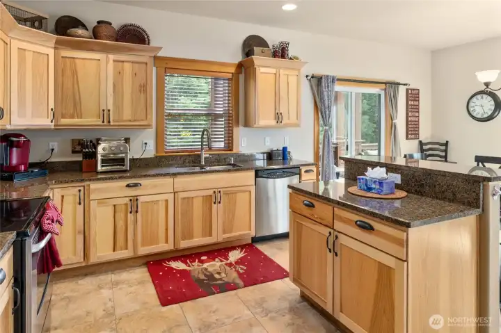 The kitchen combines hickory cabinets, elegant granite counters, and classic ceramic tile flooring.