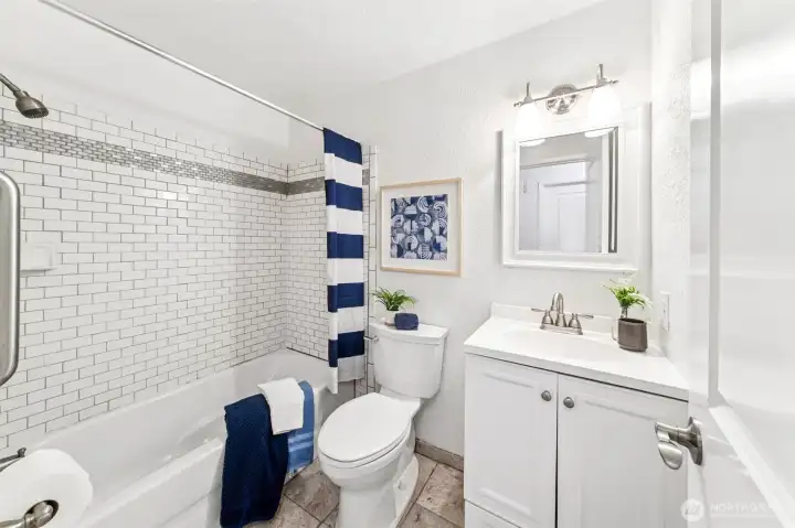 Handsome tile work with easy care grey tone grout, durable tile floors and a new bathroom vanity adorn the main bath across from the secondary bedrooms, and near the kitchen.