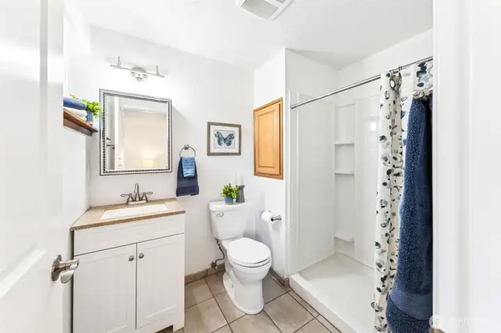 Find an easy step-in, wide shower and new vanity and comfort height, elongated commode in the primary 3/4 bath designed with minimal-care materials. Mirrored medicine cabinet plus in-wall cabinet offers plenty of storage.