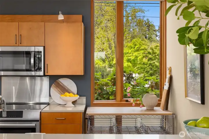 A floor to ceiling window with views of the mature landscaping keeps the kitchen bright and cheerful, while a baker’s rack with a chopping block surface provides additional utility without blocking light.