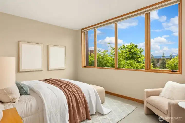 The primary bedroom’s wall of windows frame greenery and open skies, and the elevated position of this side of the home maintains a surprising degree of privacy. Hunter Douglas bottom-up, top-down blinds (throughout the home) are perfect for creating additional privacy while still enjoying the abundant natural light.